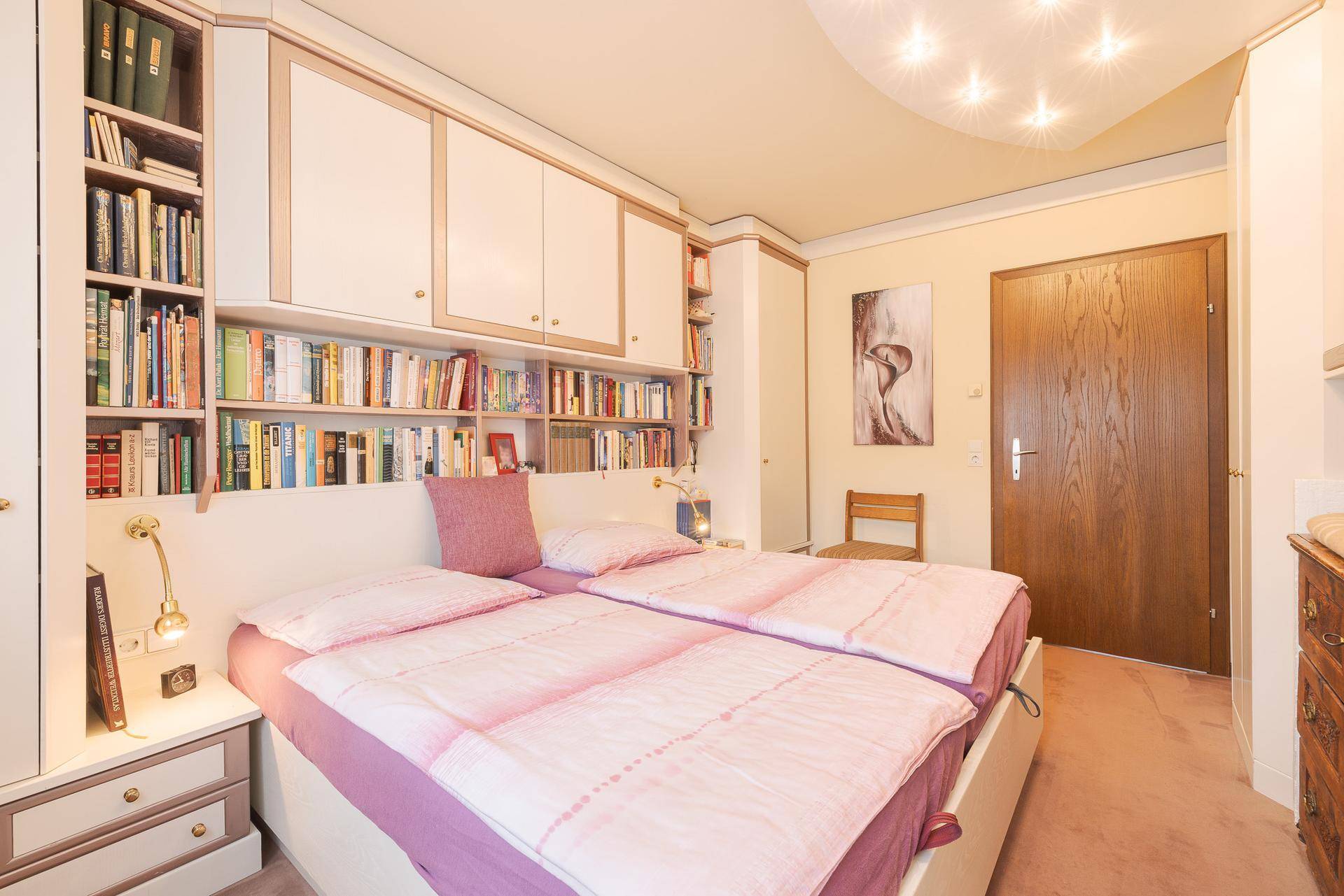 Gemütliches Schlafzimmer mit zwei Einzelbetten, integrierten Regalen und Teppichboden.