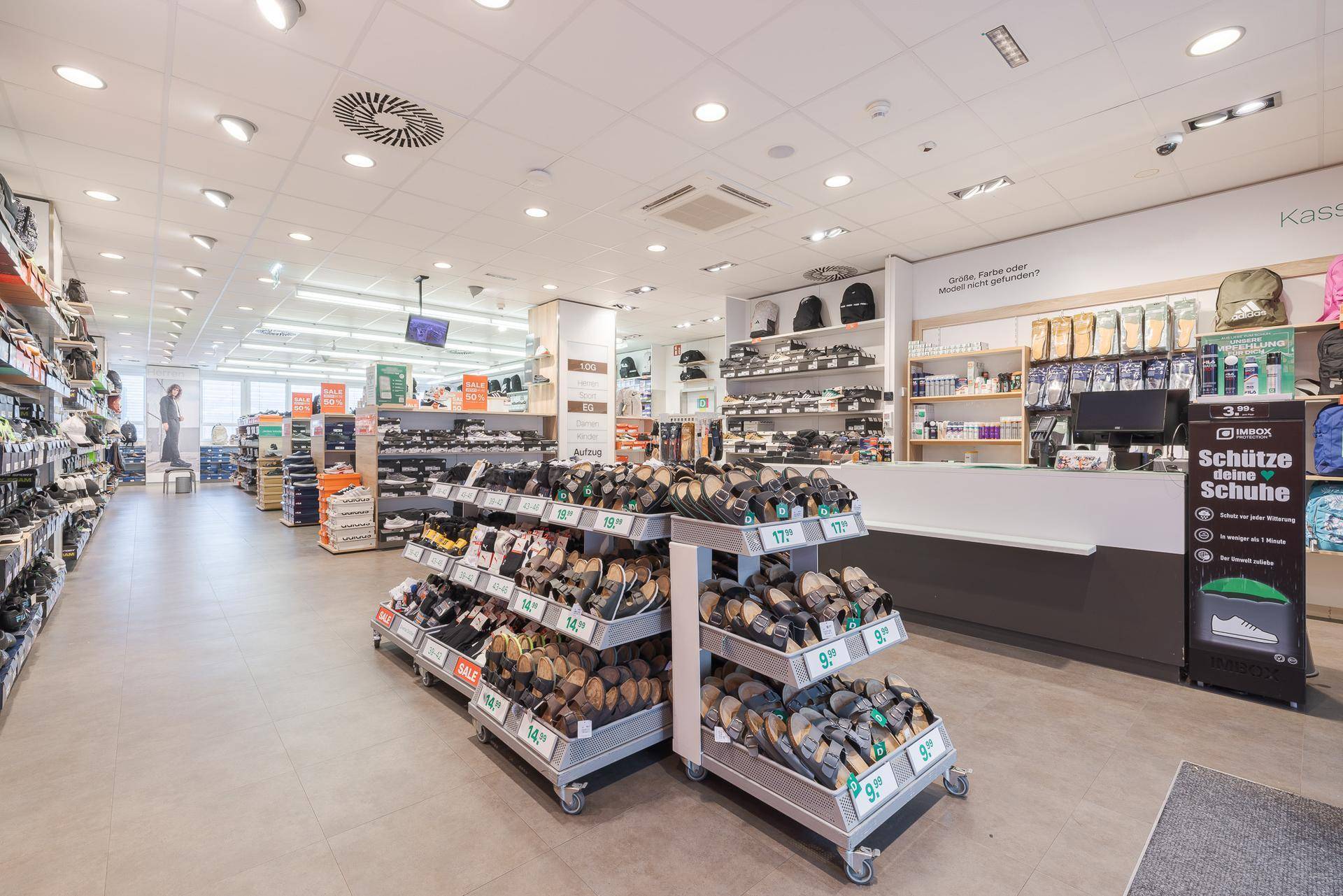 Kassenbereich eines Schuhgeschäfts mit Verkaufstheke und weiteren Produktauslagen.