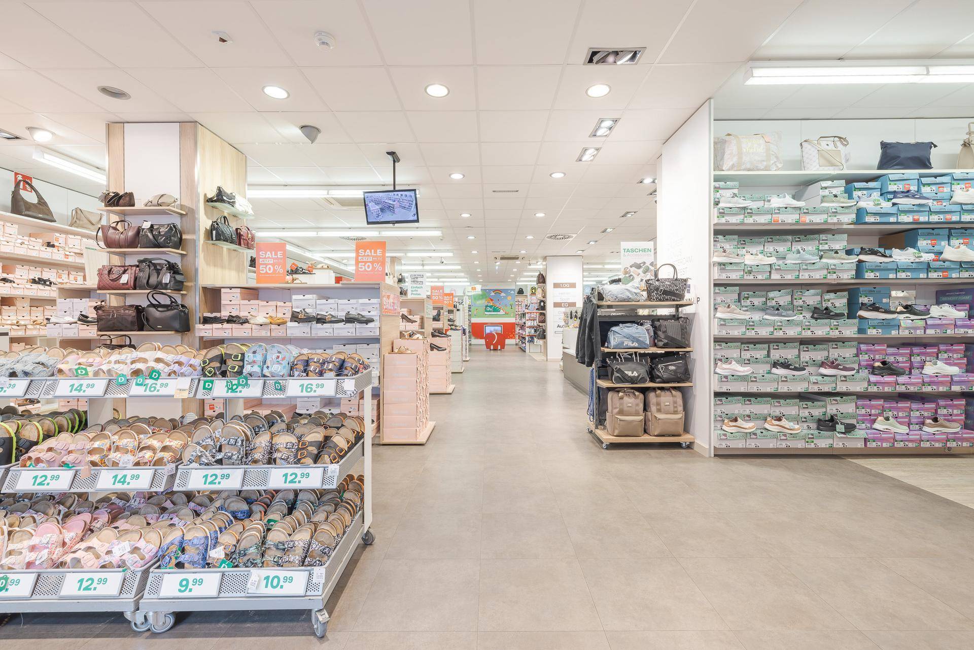 Heller Verkaufsraum eines Schuhgeschäfts mit Regalen voller Schuhe und Handtaschen.