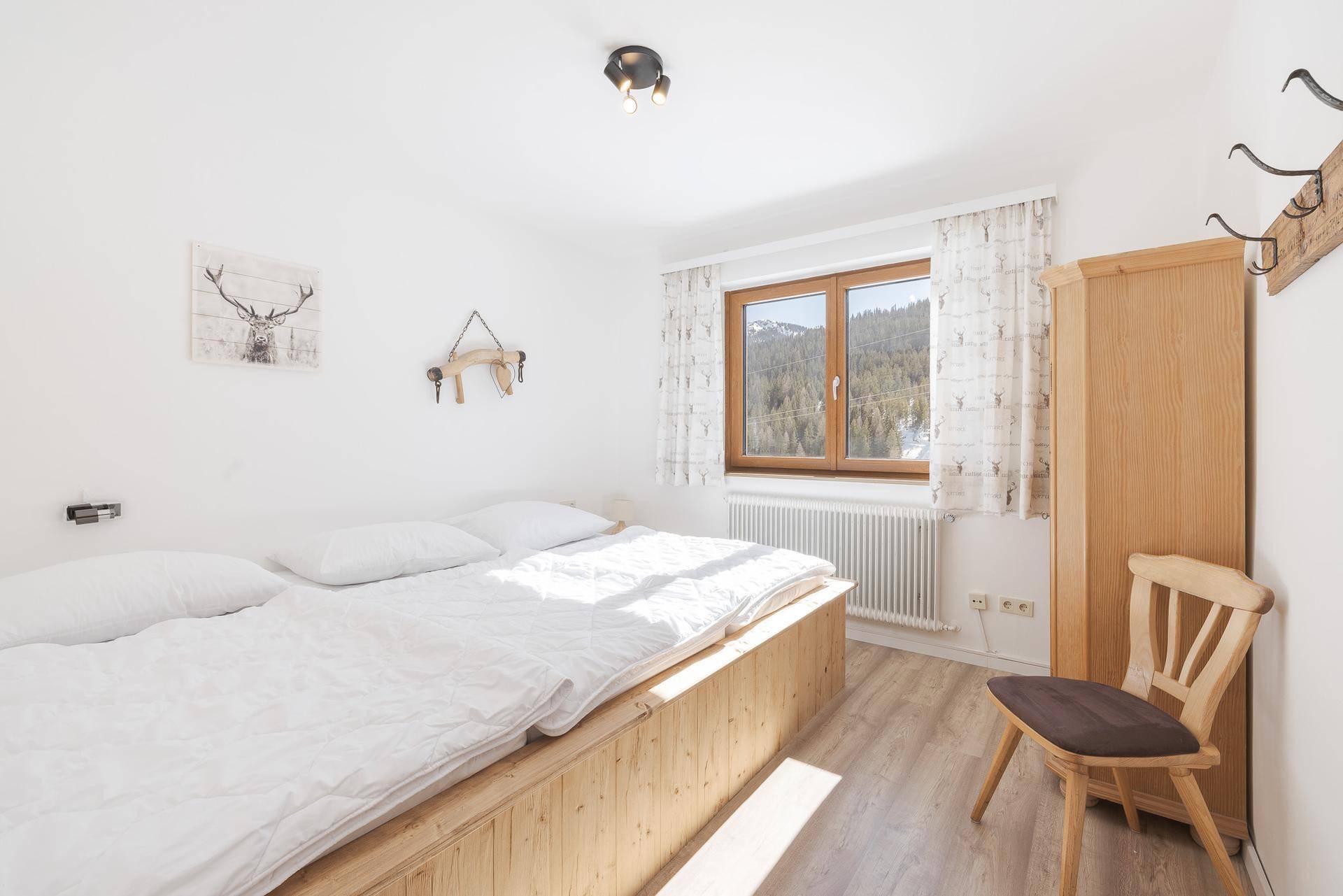Gemütliches Schlafzimmer mit Doppelbett, Holzboden und Blick auf die verschneite Landschaft.