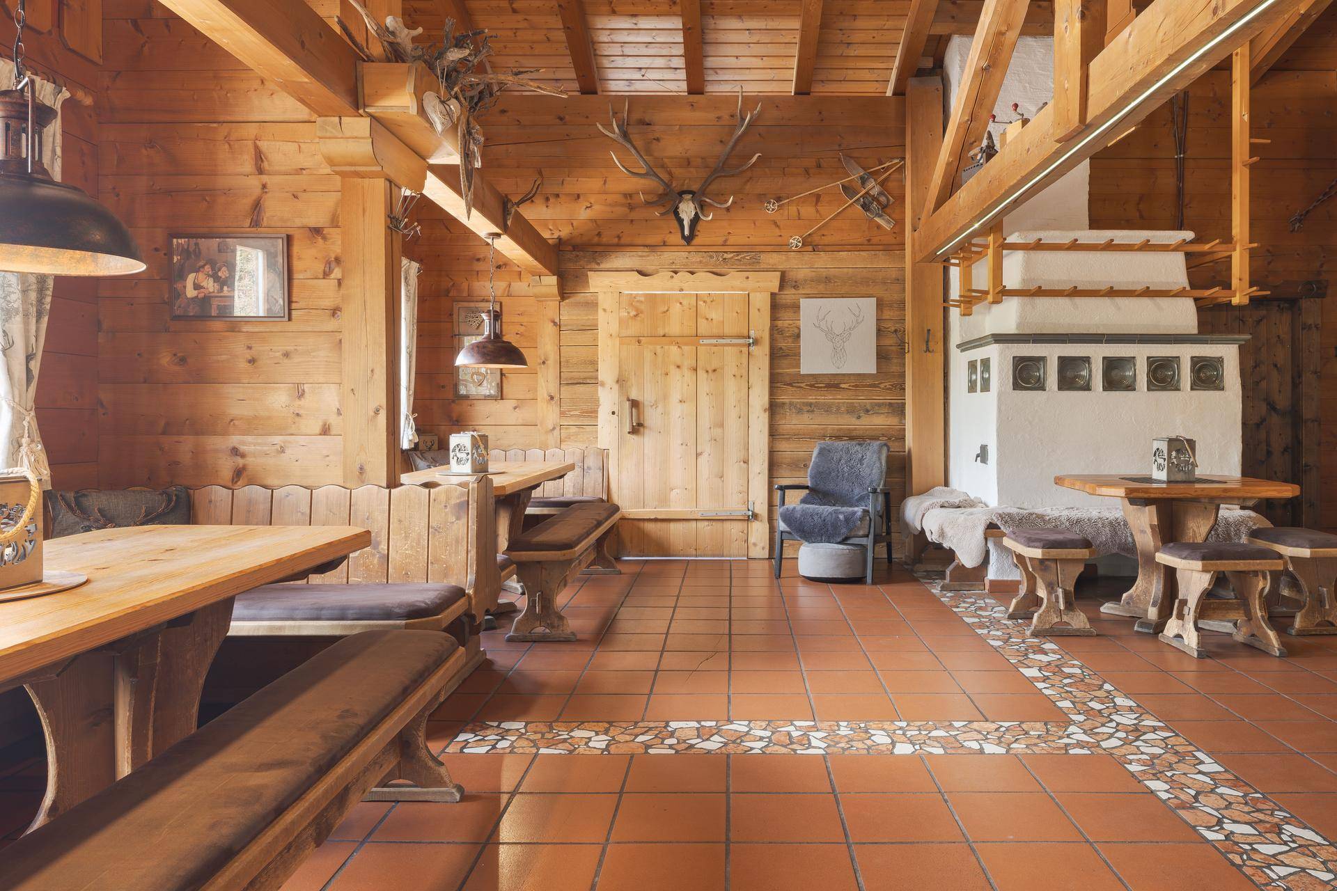 Rustikaler Speisesaal mit Holztäfelung, Hirschgeweihen als Dekoration und traditionellen Sitzgelegenheiten.