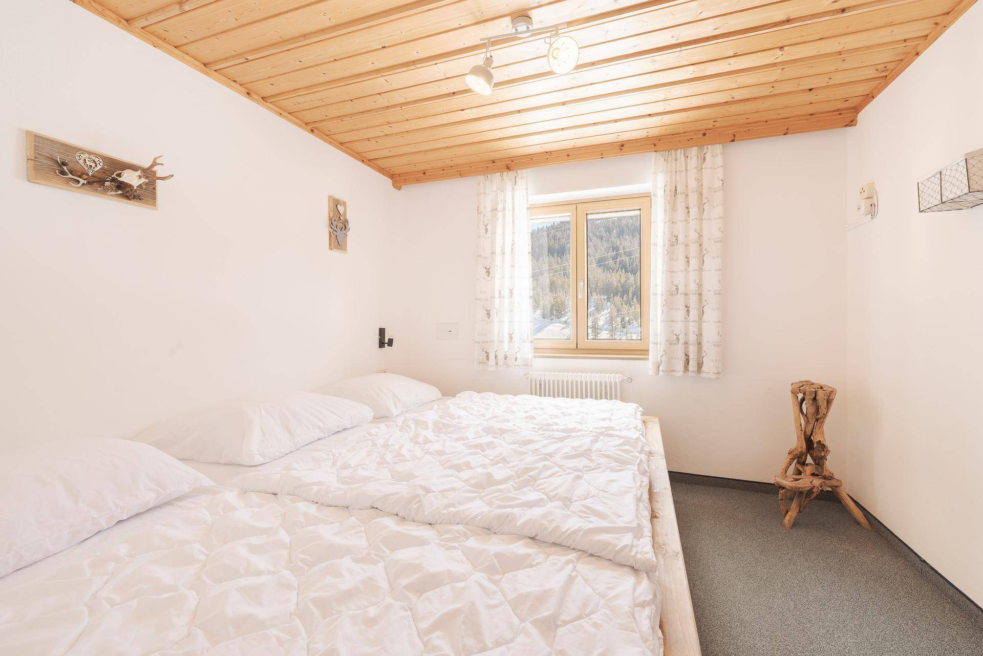Schlafzimmer mit Doppelbett, Holzdecke und Blick auf die verschneite Landschaft.