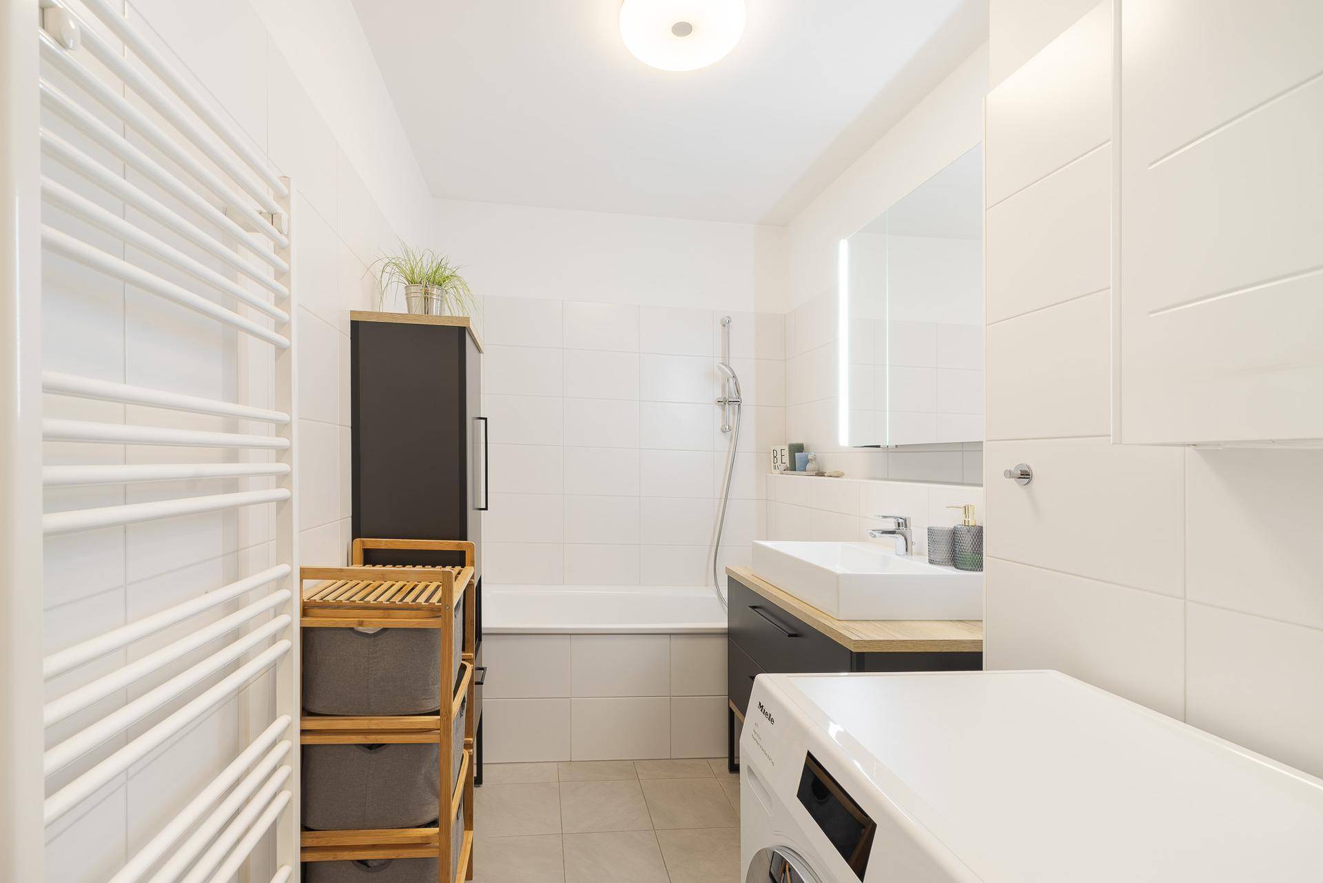 Modernes Badezimmer mit Badewanne, Waschbecken und Handtuchheizkörper.