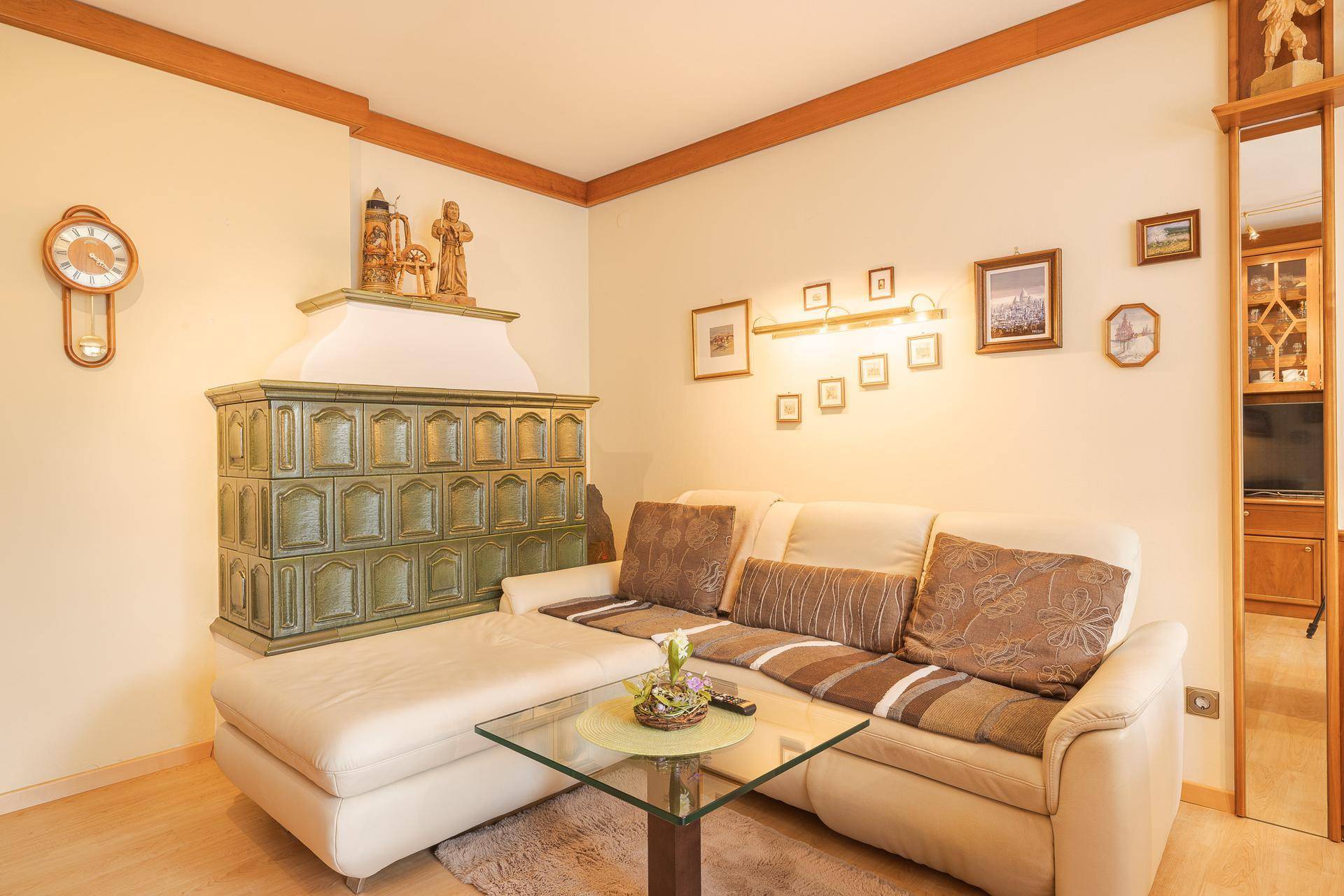 Detailansicht des Wohnbereichs mit bequemem Sofa und traditionellem Kachelofen als Blickfang.
