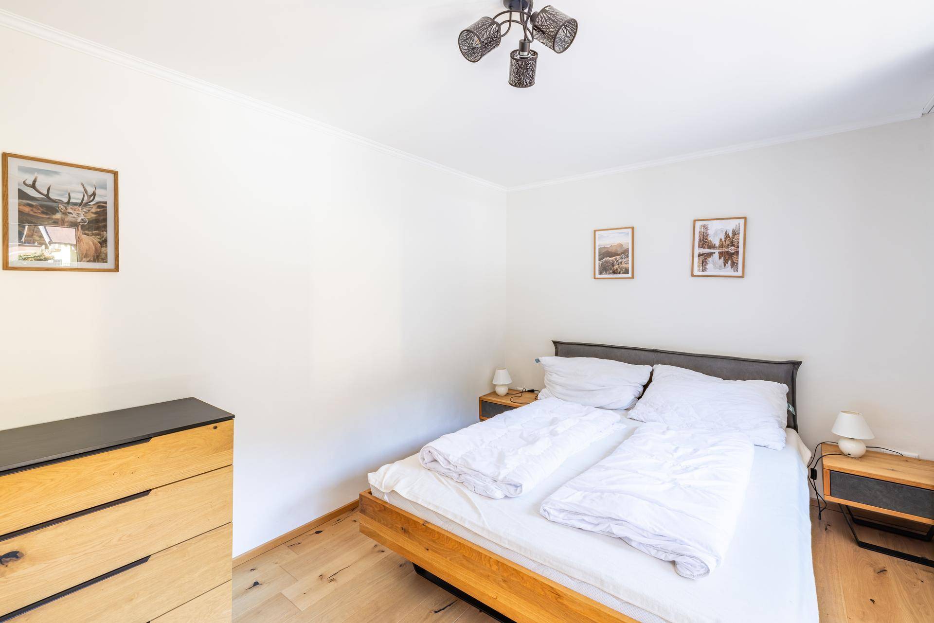 Helles Schlafzimmer mit Doppelbett, Holzboden und schlichter, moderner Einrichtung.