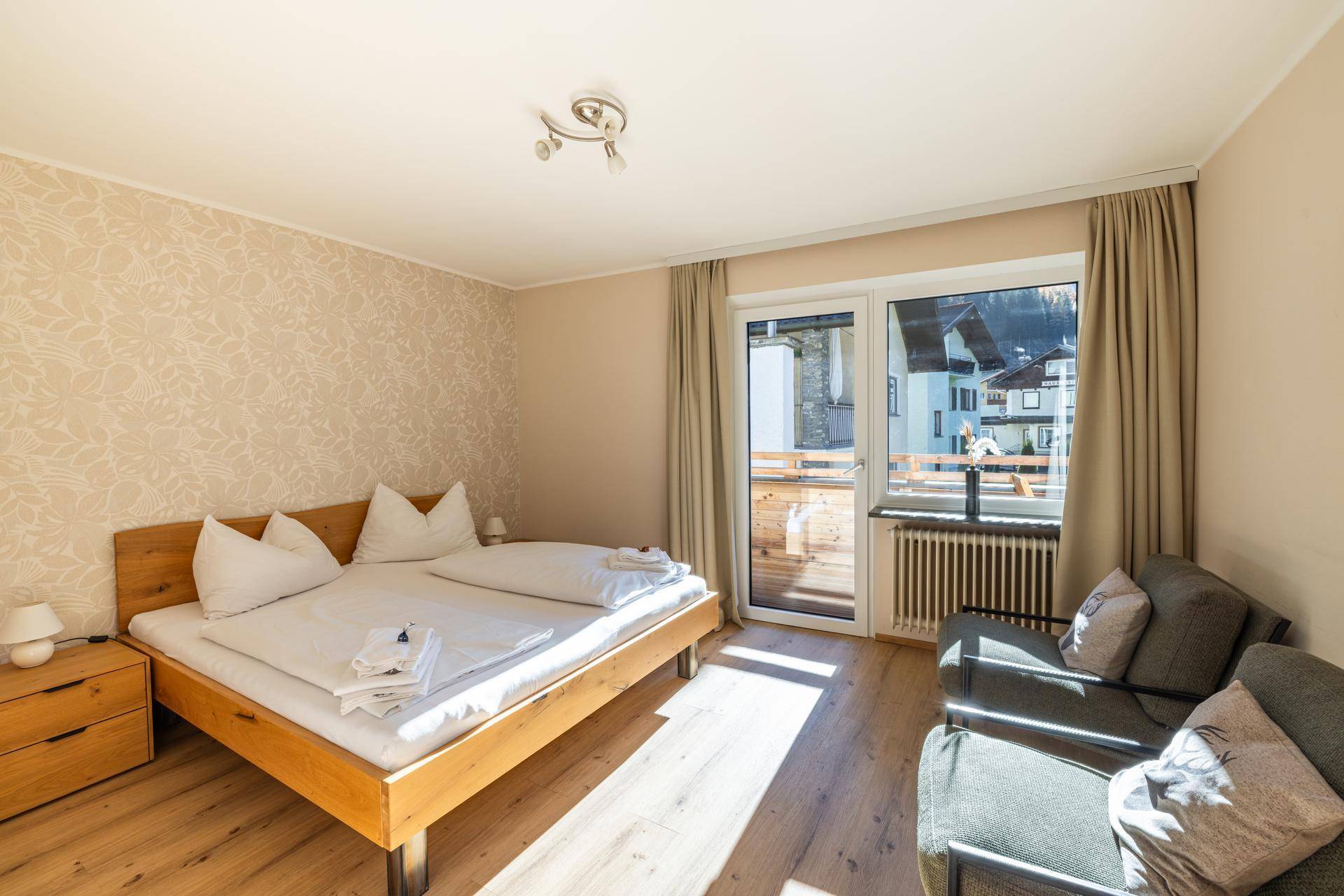 Schlafzimmer mit Doppelbett, Holzboden und direktem Zugang zu einem Balkon.