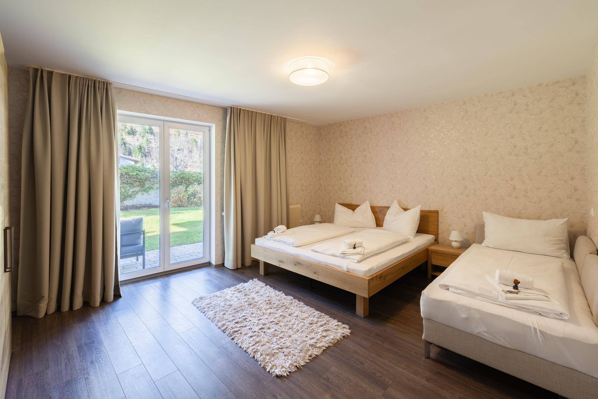 Schlafzimmer mit Doppelbett, Holzboden und direktem Zugang zum Garten.