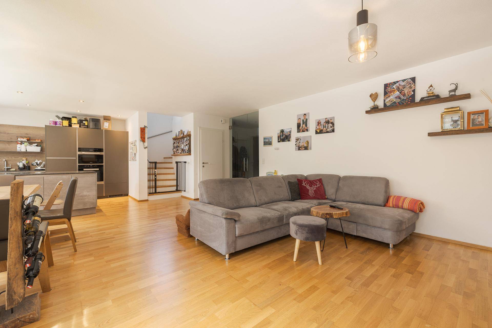 Geräumiger offener Wohnbereich mit integrierter Küche und Holzfußboden, ideal für Familienleben.