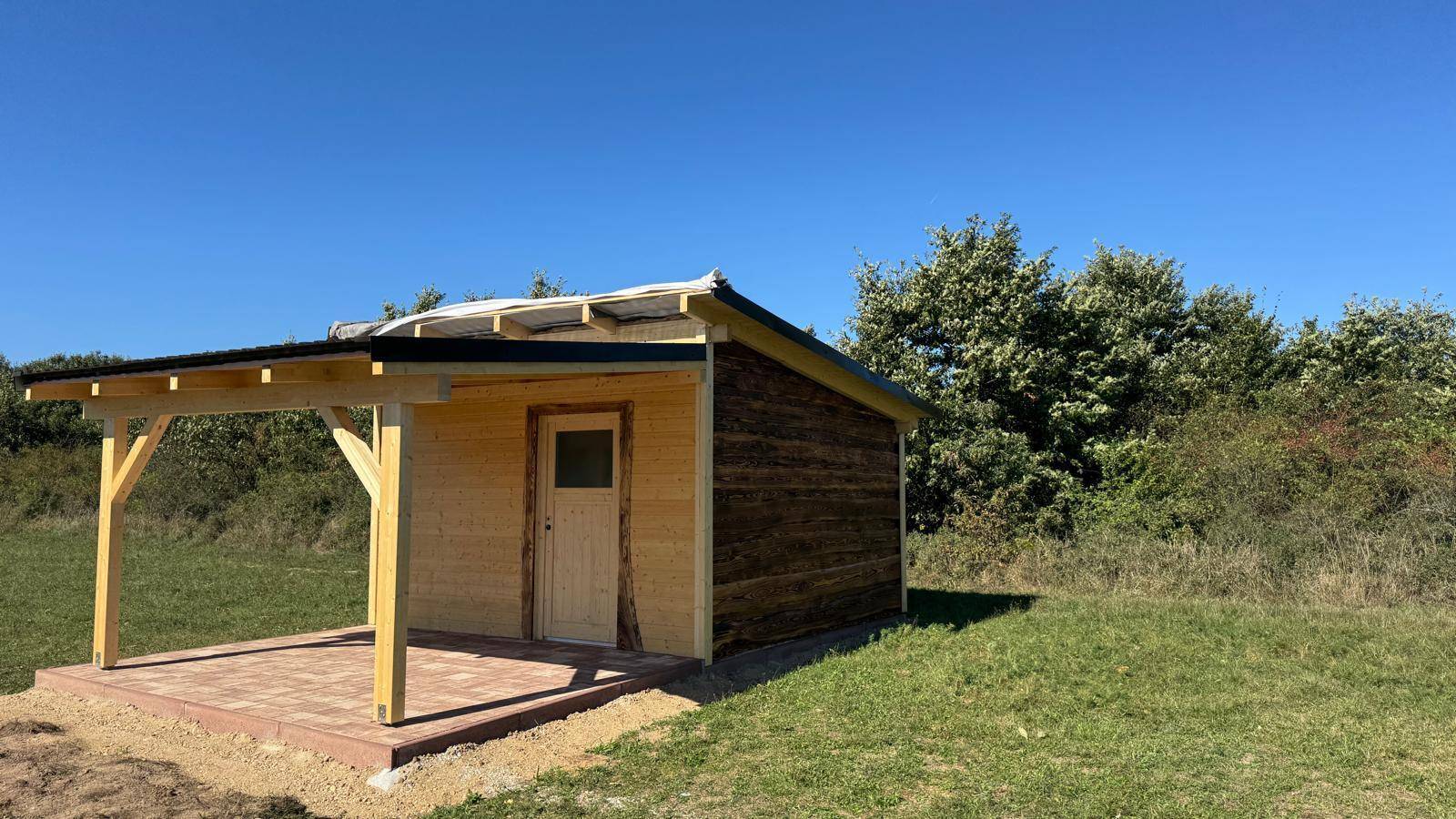 Die Holzhütte mit ihrer überdachten Veranda, umgeben von unberührter Natur.