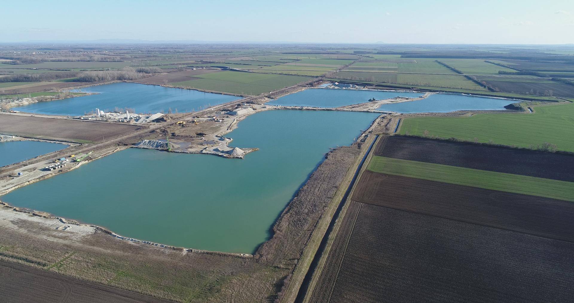 Weitläufige Luftaufnahme von mehreren Wasserflächen und landwirtschaftlichen Feldern in der Landschaft.