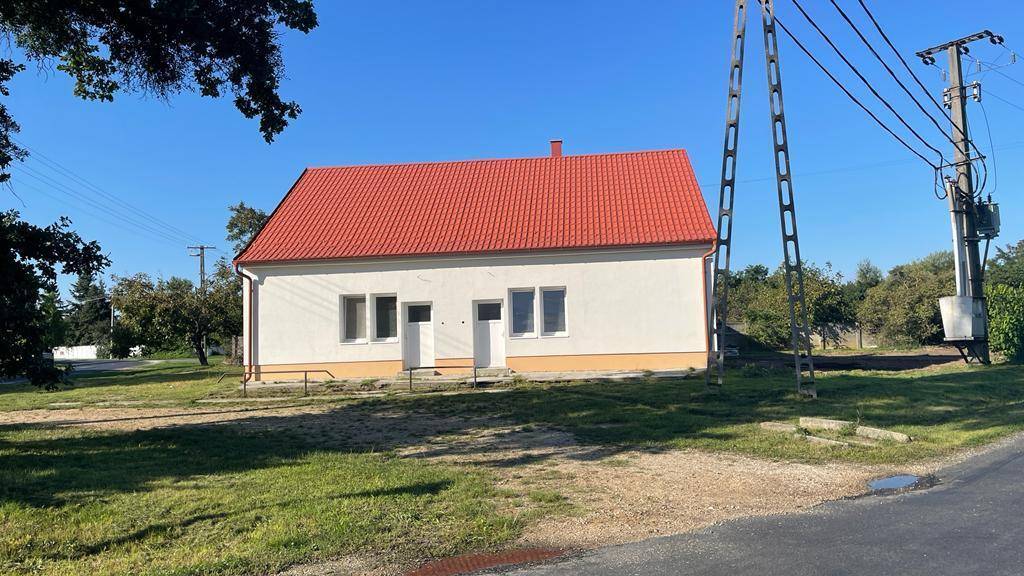 Das frisch renovierte Haus mit rotem Ziegeldach und weißer Fassade, umgeben von Grünflächen.