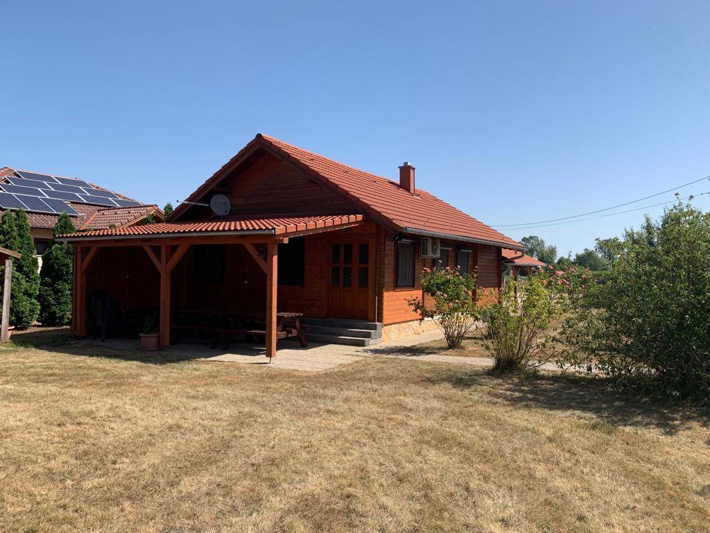 Holzhaus mit überdachter Terrasse und Garten, ideal für entspannte Stunden im Freien mit Sitzgelegenheiten.