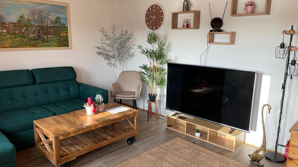 Helles Wohnzimmer mit Sofa, Holztisch und Fernseher, modern eingerichtet.
