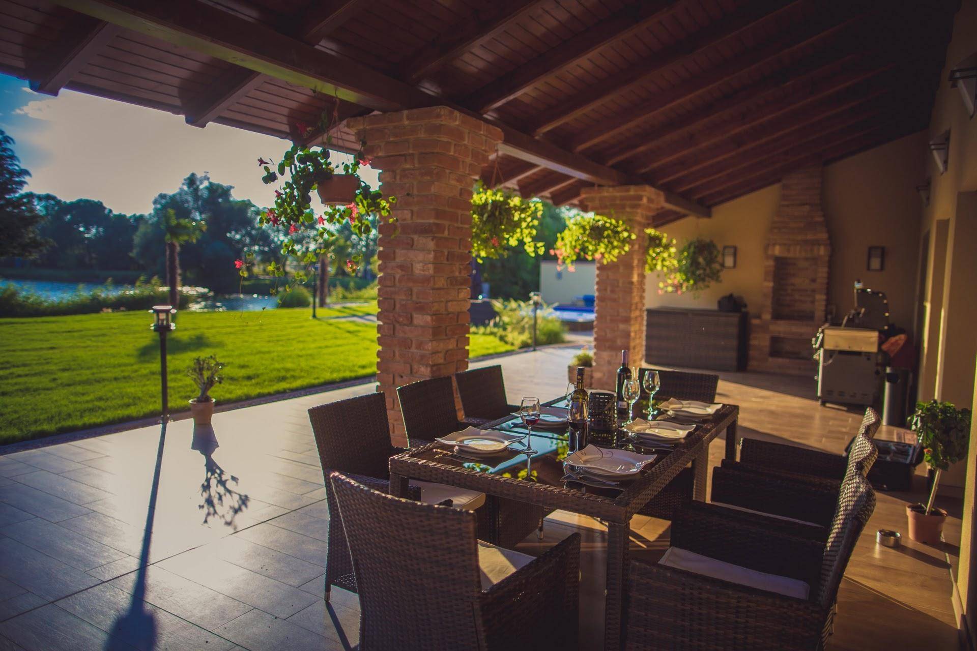 Einladende überdachte Terrasse mit Esstisch und Blick auf den See und den grünen Garten.