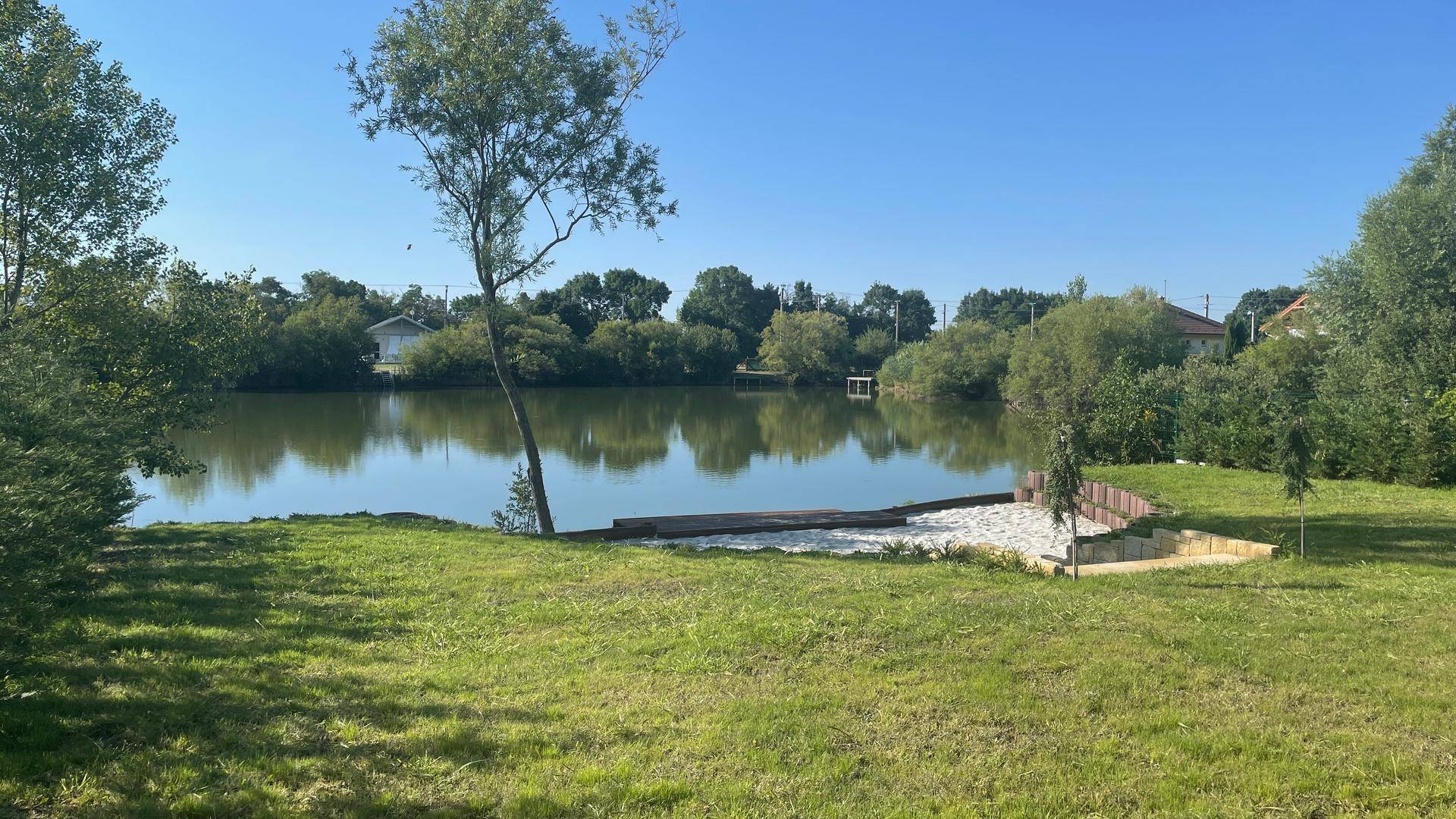 Weitläufiger Gartenbereich mit Rasen und Blick auf den See.