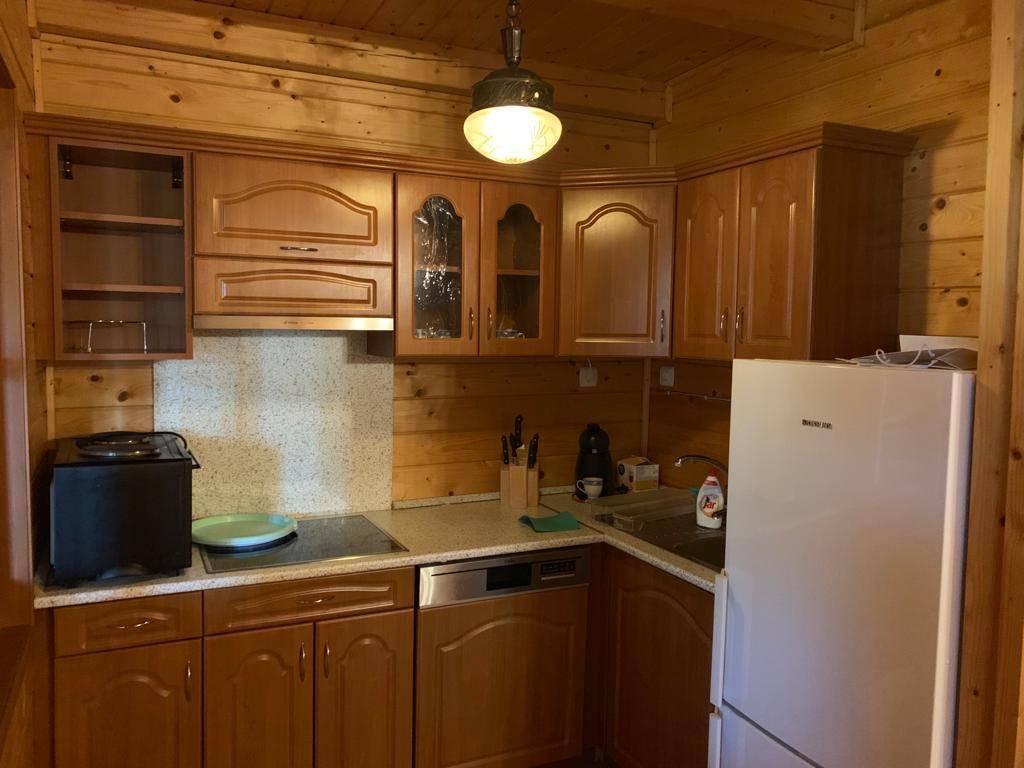 Küche mit Holzschränken, Einbaugeräten, Kühlschrank, Geschirrspüler und einem Fenster.