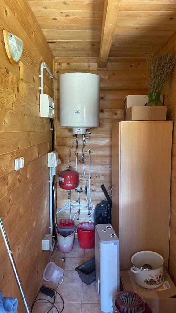 Praktischer Hauswirtschaftsraum mit Warmwasserbereiter, Leitungen und Stauraum.