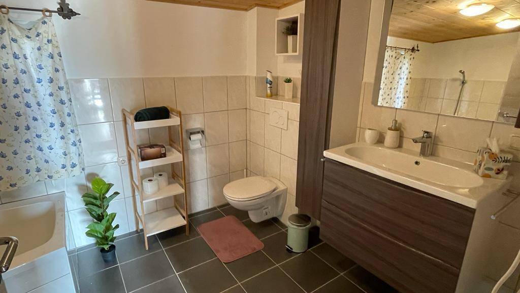 Badezimmer mit WC, Waschbecken und Badewanne, hell gefliest.