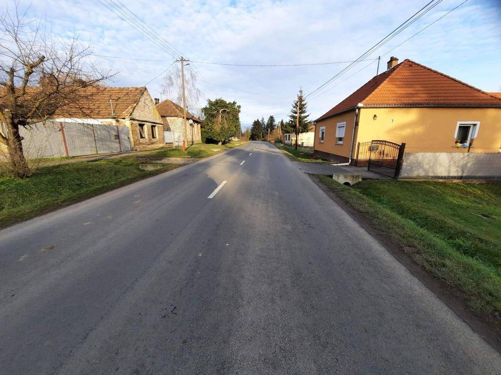Ländliche Straße mit traditionellen Häusern und klarem Himmel an einem sonnigen Tag.