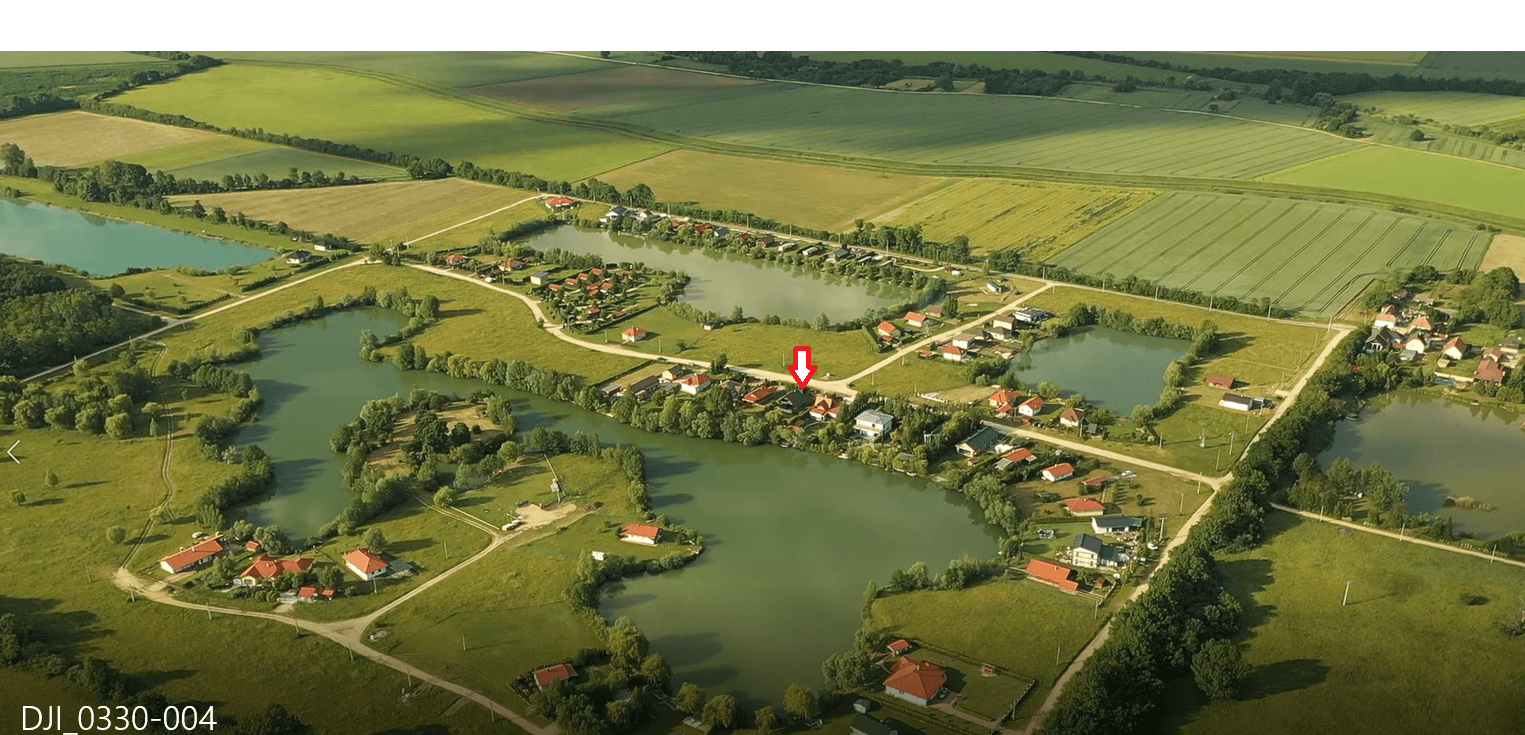 Panoramische Luftaufnahme einer Seenlandschaft mit zahlreichen Häusern und dem markierten Grundstück.