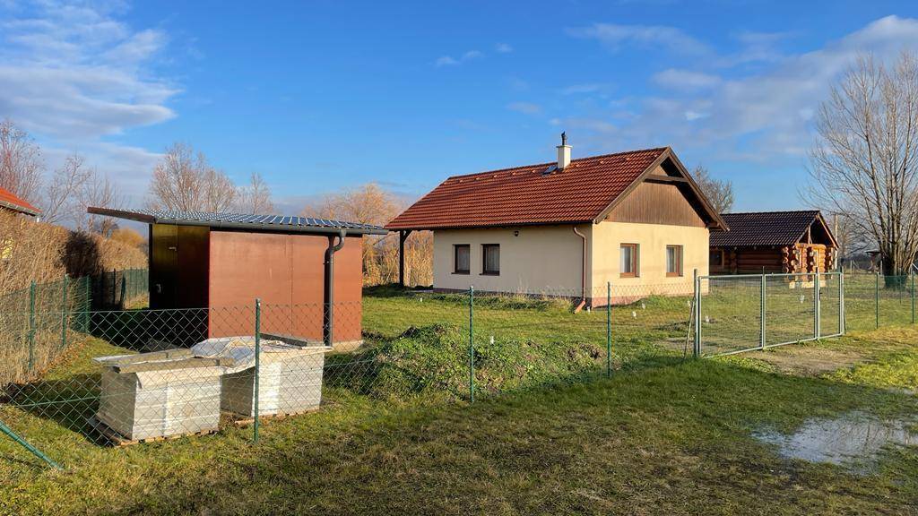 Haus mit Satteldach und Nebengebäude auf einem weitläufigen, umzäunten Grundstück.