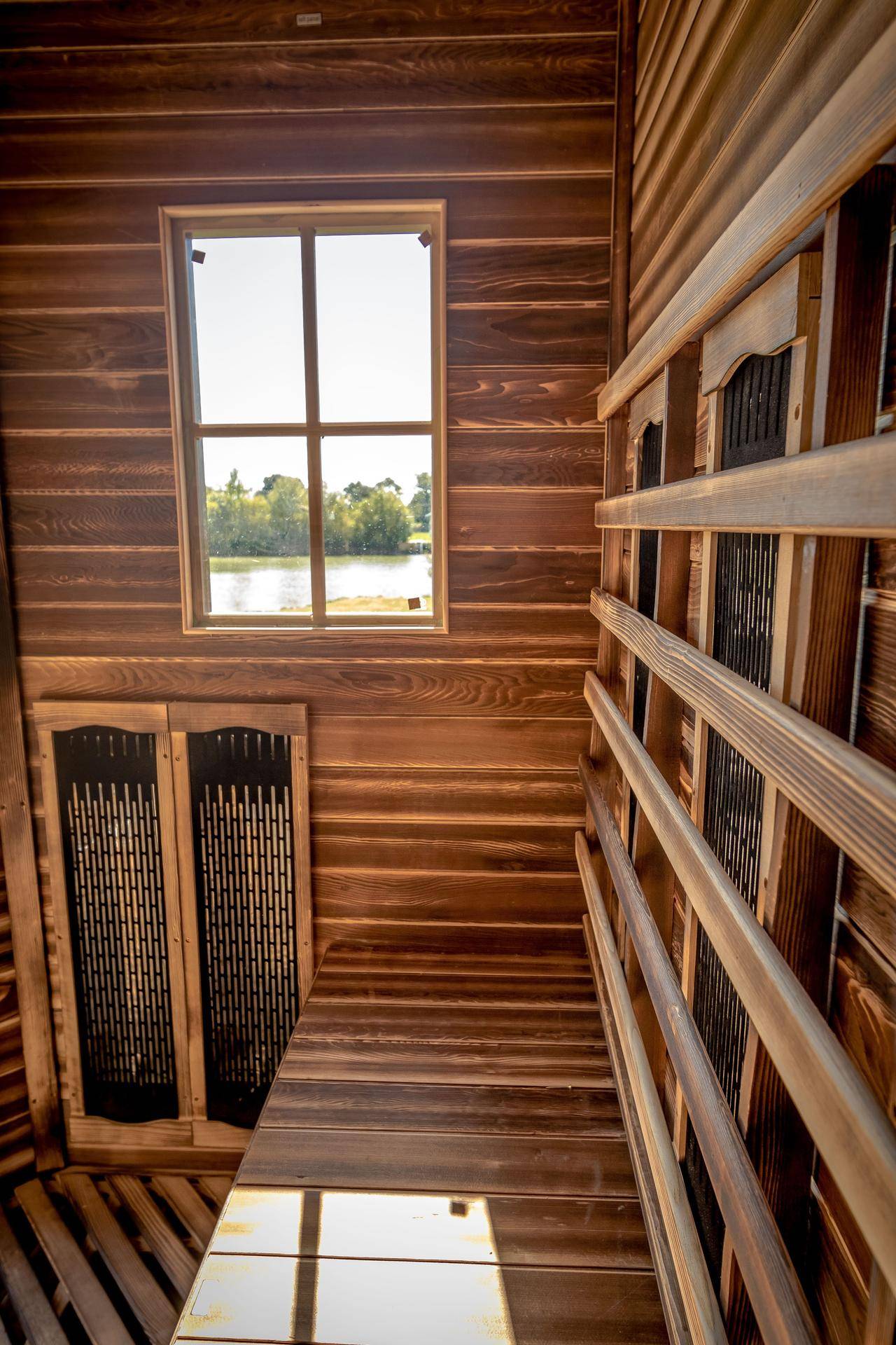 Innenansicht der Holzsauna mit Holzbänken und Fenster mit Seeblick.