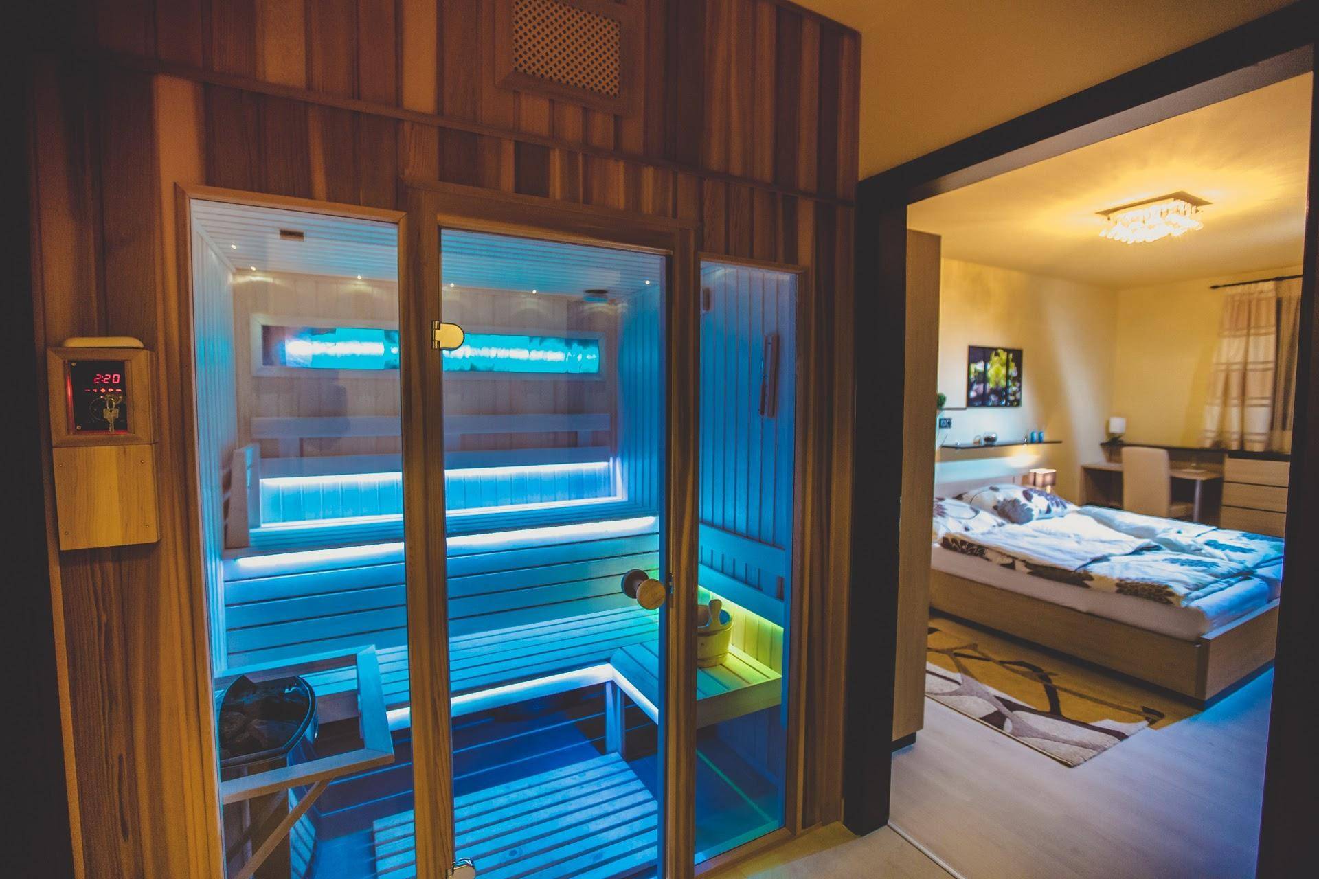 Moderne Sauna mit blauer Beleuchtung, die einen Blick in ein angrenzendes Schlafzimmer bietet.