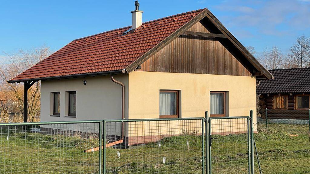 Freistehendes Haus mit Ziegeldach und Holzgiebel, umgeben von einem Zaun.