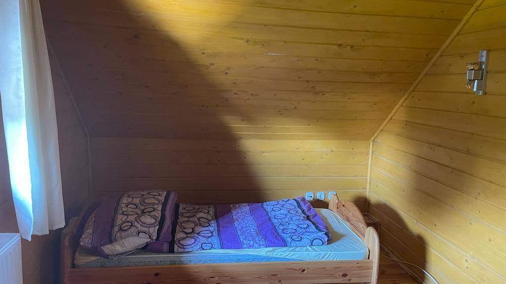 Gemütliches Schlafzimmer im Dachgeschoss mit schrägen Holzdecken und einem Einzelbett.