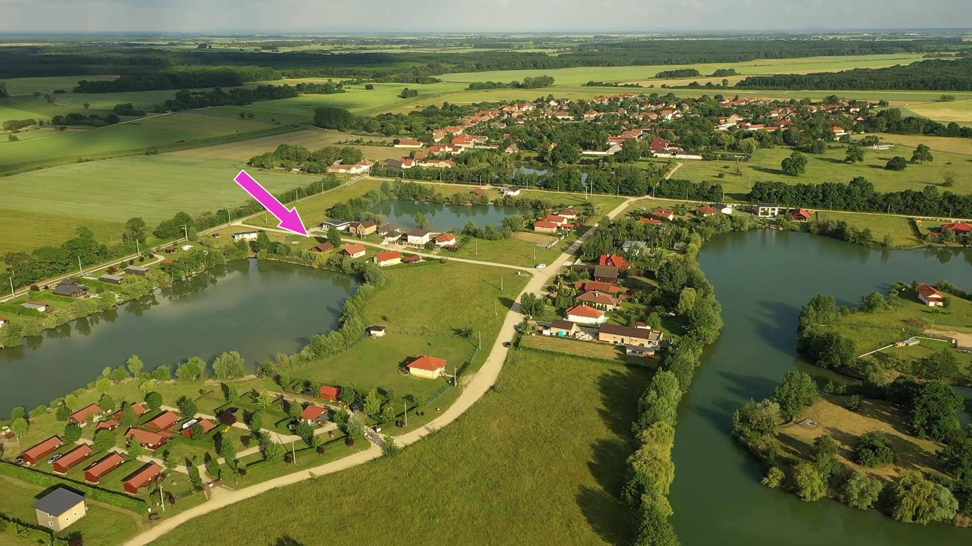 Weitläufige Luftaufnahme der Seenlandschaft mit umliegenden Häusern und Feldern unter klarem Himmel.