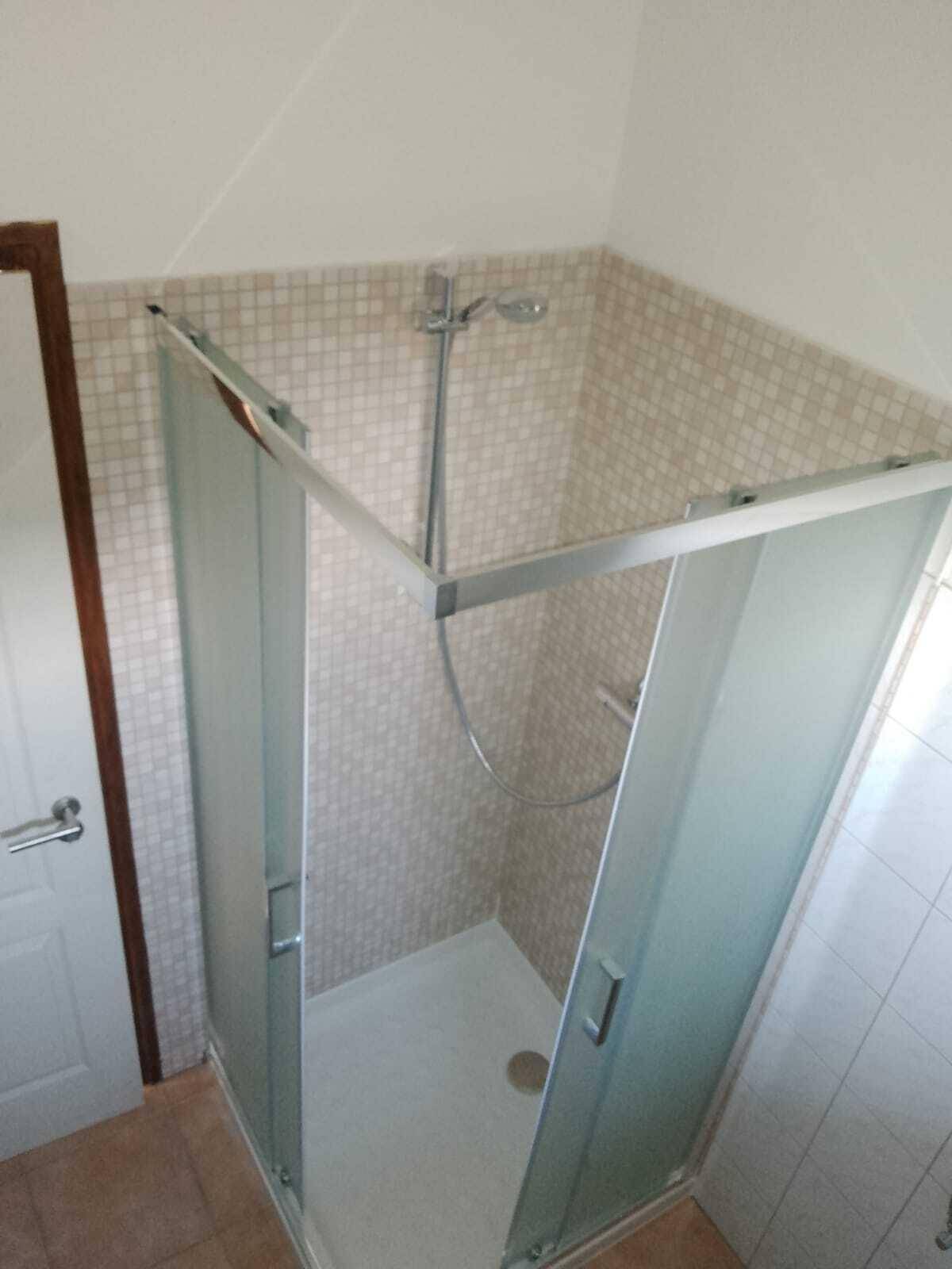 Badezimmer mit Duschkabine und hellen Fliesen, funktional und sauber.