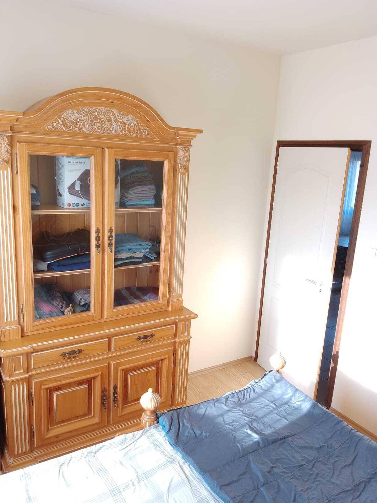 Schlafzimmer mit traditionellem Holzschrank und Bett, hell durch das Fenster.