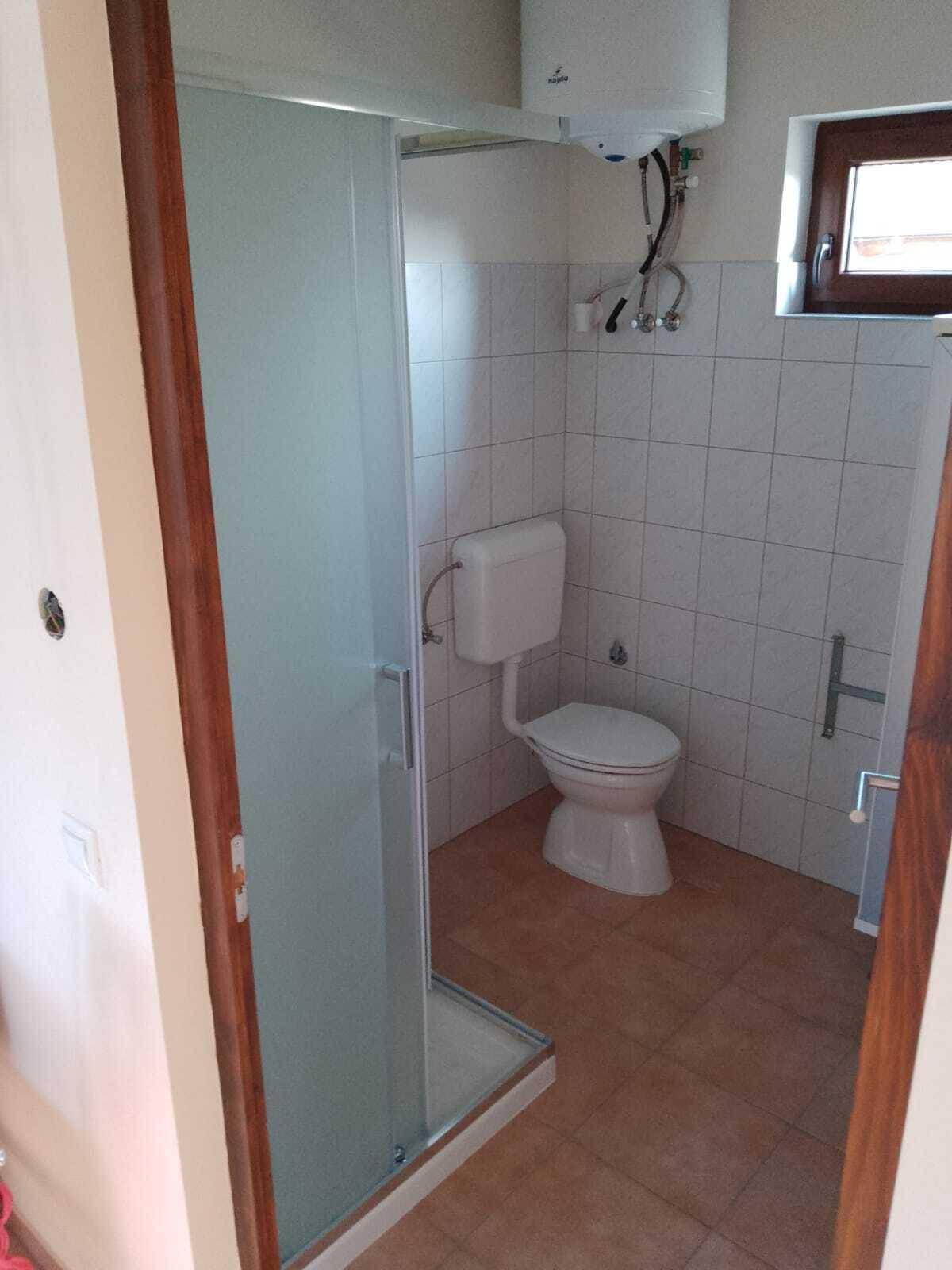 Badezimmer mit Toilette, Duschkabine und Fenster, einfach und funktional.