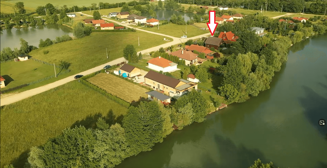 Luftaufnahme eines Wohngebiets mit mehreren Seen und Häusern, wobei ein Objekt markiert ist.