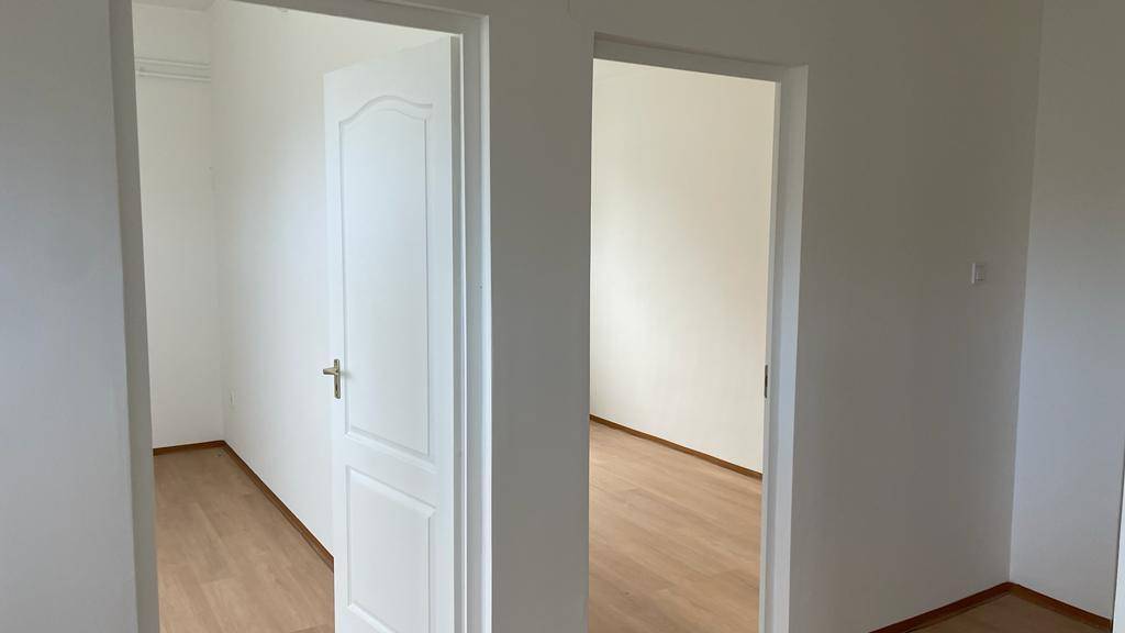 Heller Flur mit Laminatboden und weißen Türen, die zu verschiedenen Räumen führen.