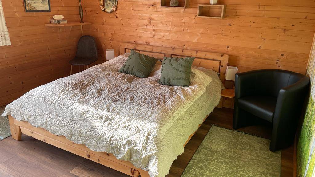 Schlafzimmer mit Doppelbett, Holzwänden und gemütlicher Einrichtung.