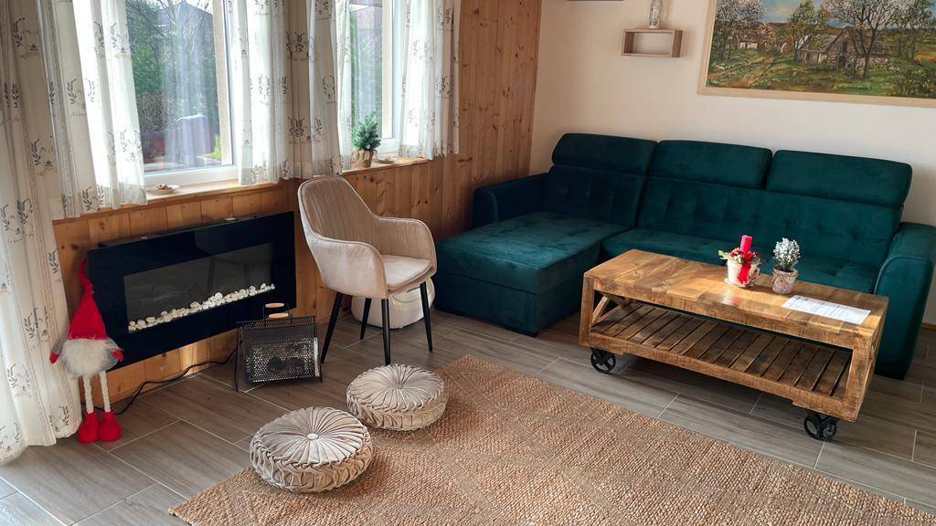Wohnzimmer mit Sofa, Kamin und Holzwänden, gemütlich eingerichtet.