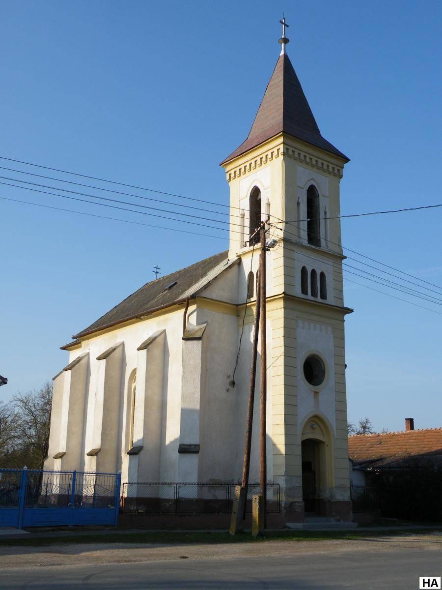 Historische Kirche mit hohem Turm und traditioneller Architektur unter blauem Himmel.