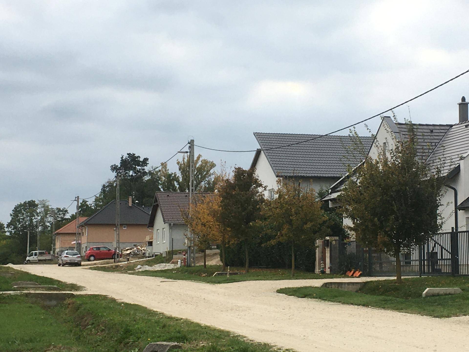 Seeufer mit einem Entwässerungsrohr und grüner Vegetation unter bewölktem Himmel.