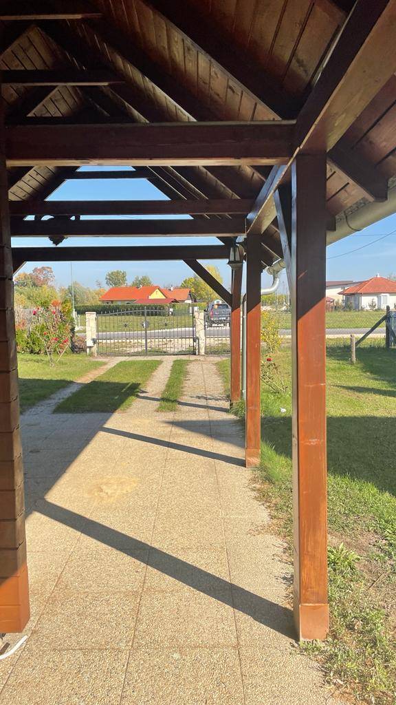 Überdachter Eingangsbereich mit Holzbalken und gepflastertem Weg zum Gartentor.