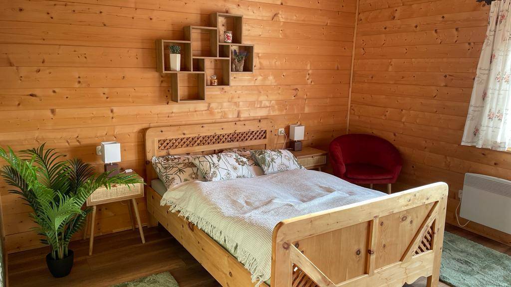 Schlafzimmer mit Doppelbett, Holzwänden und dekorativen Regalen.