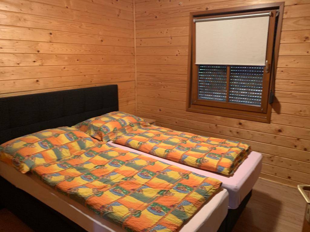 Schlafzimmer mit zwei Einzelbetten und Holzvertäfelung, bietet eine gemütliche Atmosphäre mit Rollladen am Fenster.