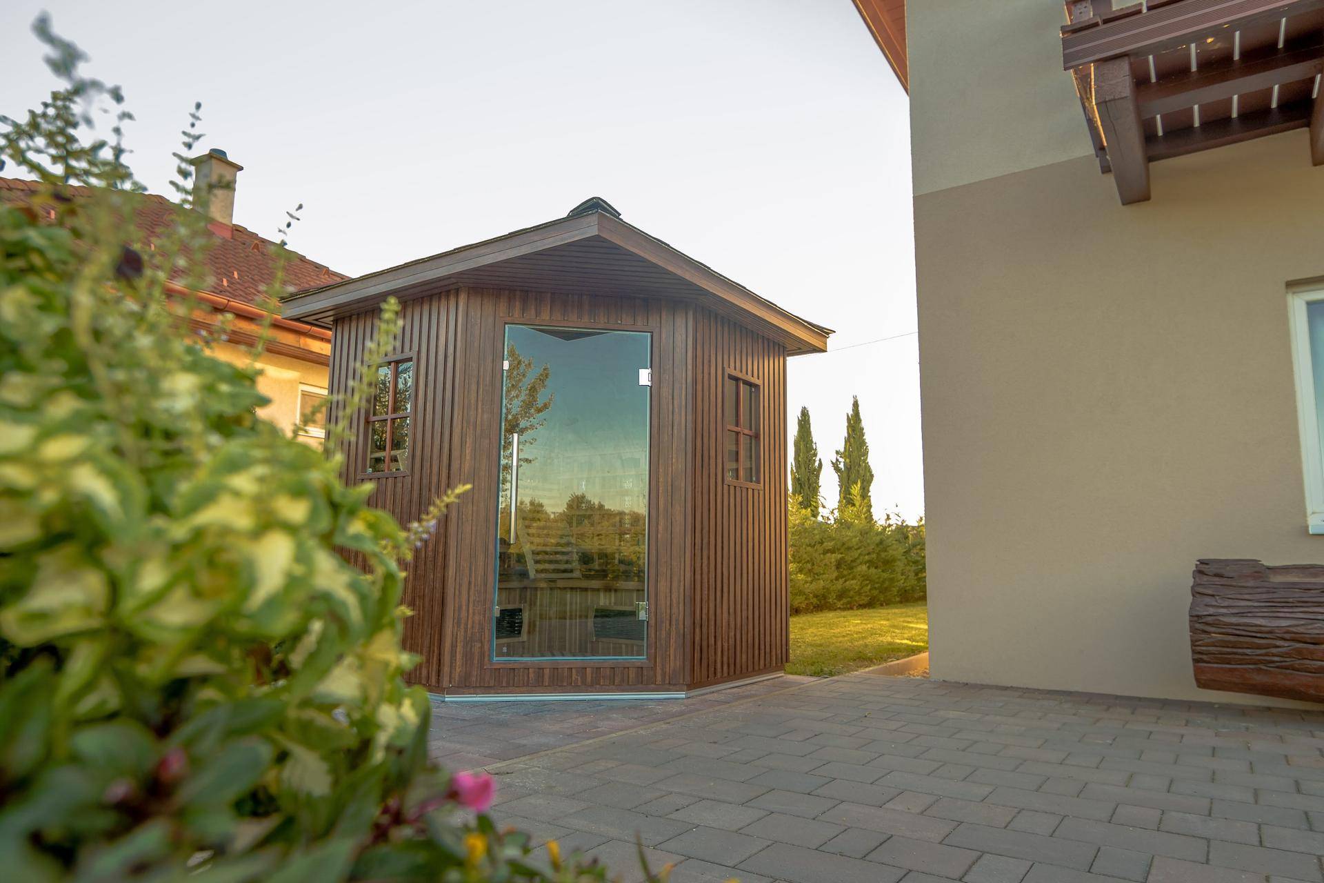 Moderne Holzsauna im Garten mit Glasfront und Blick ins Grüne.