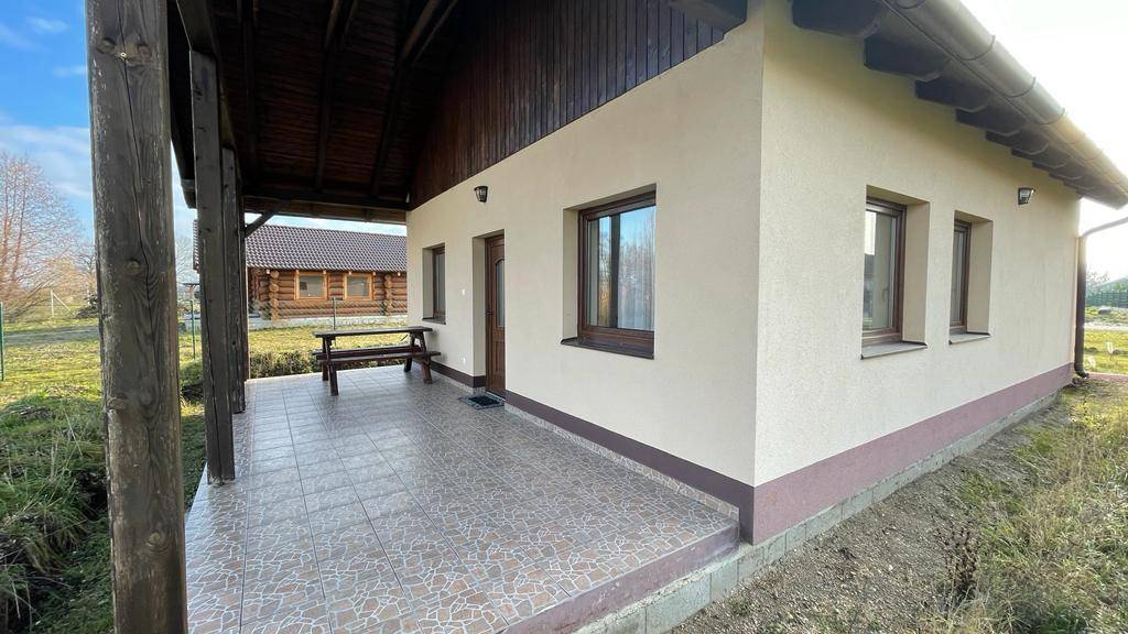 Überdachte Veranda mit gefliestem Boden und Holztisch, ideal für Mahlzeiten im Freien.