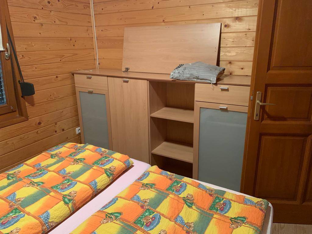 Schlafzimmer mit zwei Einzelbetten und einem Holzschrank in holzvertäfeltem Raum.