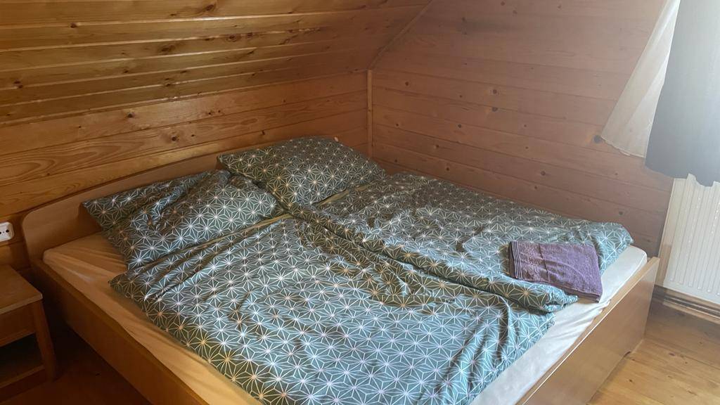 Helles Schlafzimmer mit Doppelbett, Holzvertäfelung und schräger Decke im Dachgeschoss.