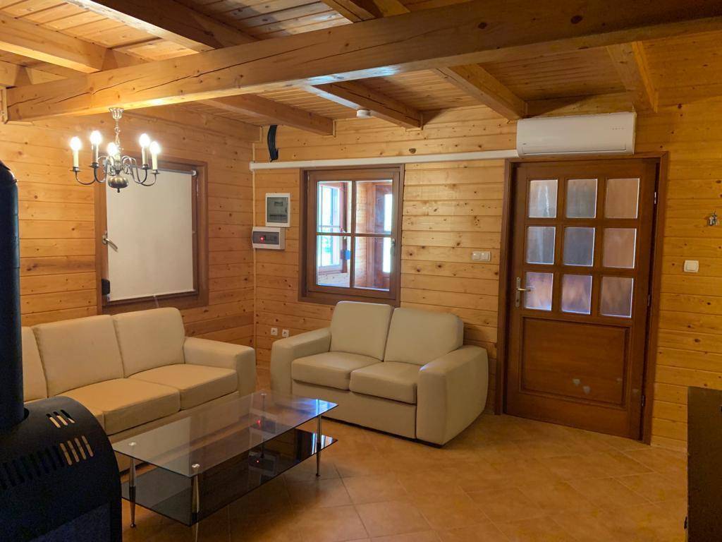 Gemütliches Wohnzimmer mit Holzvertäfelung, Kaminofen, beigen Sofas und Klimaanlage.