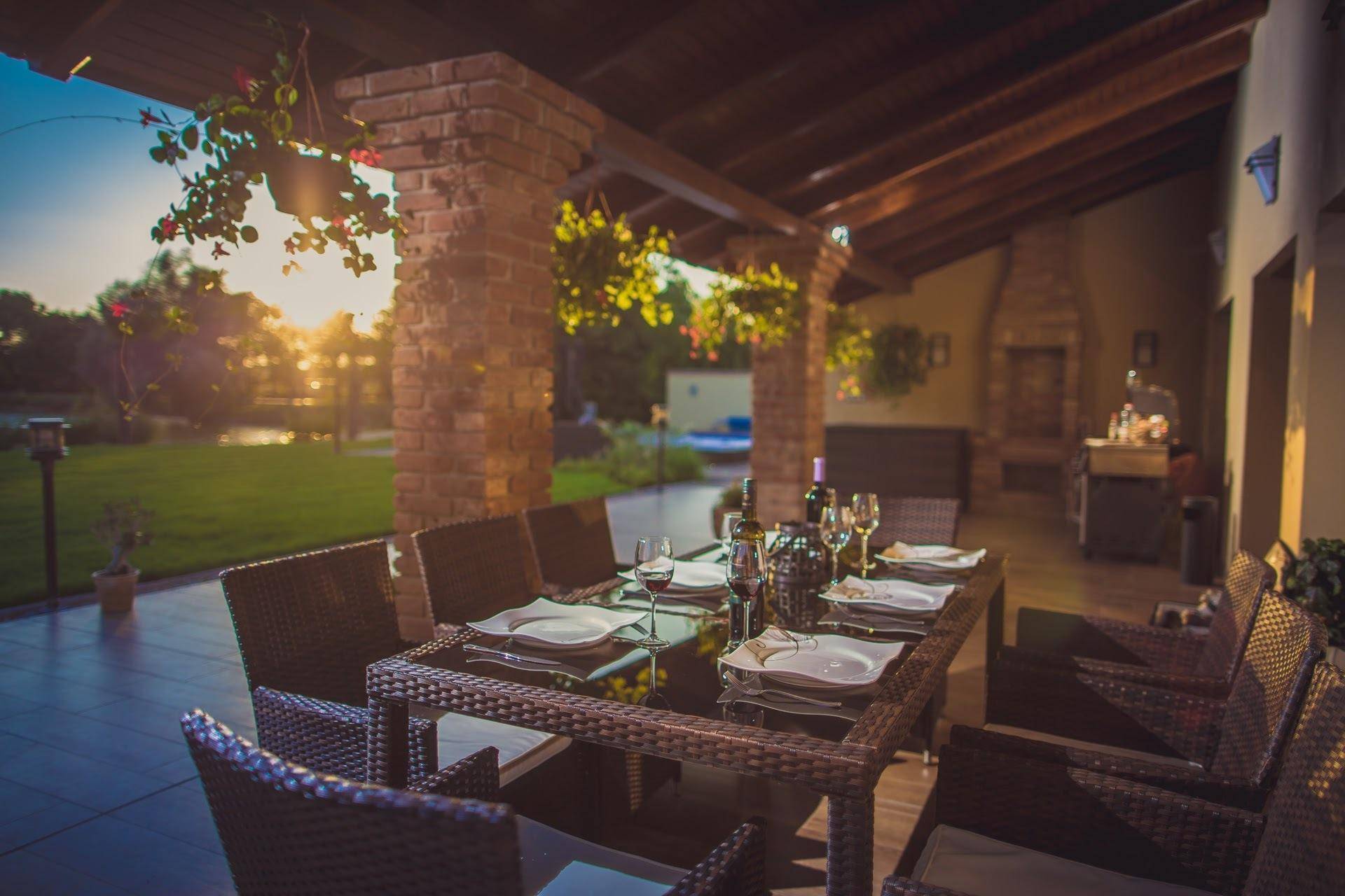 Stimmungsvolle überdachte Terrasse bei Sonnenuntergang, mit gedecktem Tisch und Seeblick.