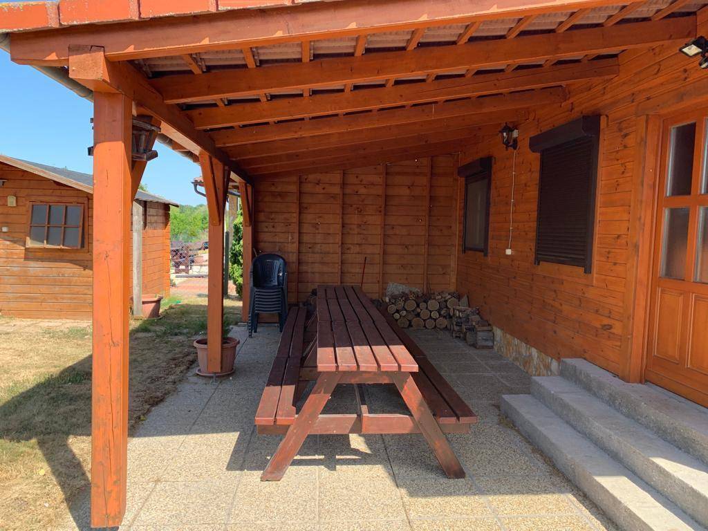 Überdachter Außenbereich mit Holztisch und Bänken, perfekt für Mahlzeiten im Freien am Holzhaus.