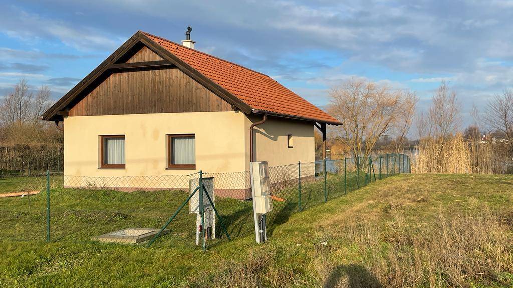 Freistehendes Haus mit Satteldach und umzäuntem Grundstück am Seeufer.
